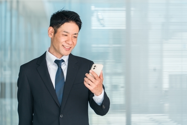 ビジネスマンがスマホ見てほほ笑んでいる写真