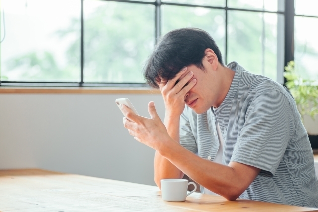 スマホを見て悩む男性