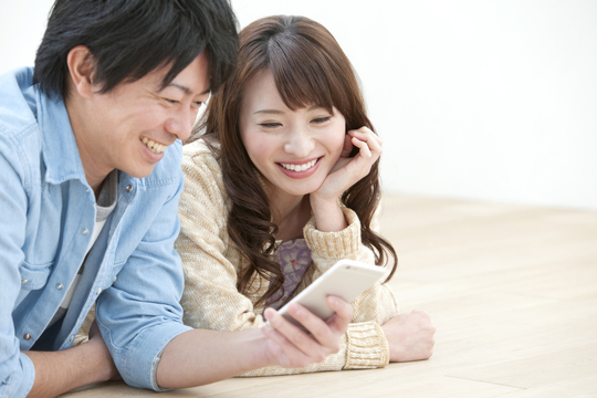 スマホを見て微笑みあうカップル